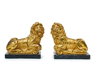 paire de serre-livres en forme de lions en or, posés sur un socle en marbre noir