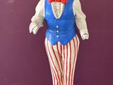 une statue représentant un homme portant un gilet rouge, blanc et bleu et un nœud papillon