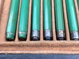 six green pens are in a case on a blue surface