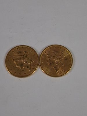 two gold coins sitting on a white surface
