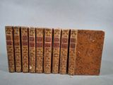 six vieux livres alignés sur une surface grise