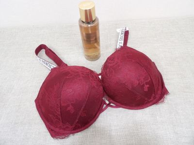 a bottle of perfume next to a bralette on a table