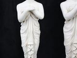 pair of white marble statues of a woman and a man on a black background