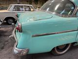a blue car parked in a garage with other cars in the background