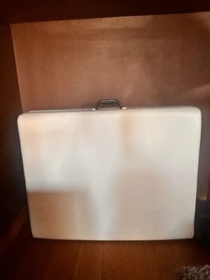 une valise blanche posée sur un parquet