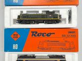 trois trains miniatures dans leurs boîtes, empilés les uns sur les autres sur une surface blanche