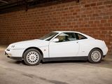 a white car that is parked in front of a brick wall