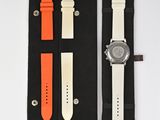 an orange and white watch sitting on top of a black case
