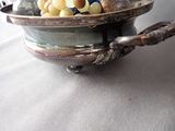 a silver bowl with grapes and nuts in it on a table