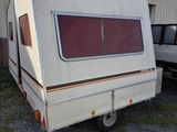 a white trailer with a red window parked in front of a building
