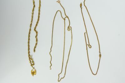 three gold necklaces and a necklace with a cross on a white background