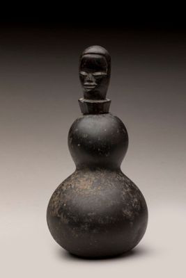 un vieux vase noir orné d'un visage sur le dessus