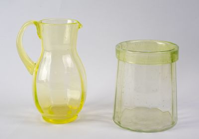 des pichets en verre jaunes et verts posés côte à côte sur une surface blanche