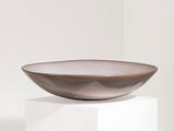 the bowl is sitting on top of a pedestal in a white room