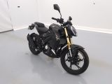 a black motorcycle parked in a room with a white wall