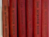 several red books are lined up on a shelf in a row