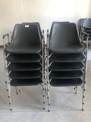 Plusieurs chaises noires sont alignées en rang dans une pièce