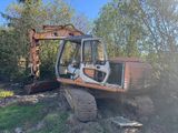 an orange and black excavator sitting on top of a grass covered field