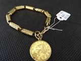 Gros plan sur un bracelet en or orné d'une pièce de monnaie