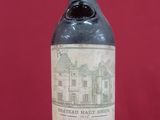 an old bottle of wine sitting on top of a red table
