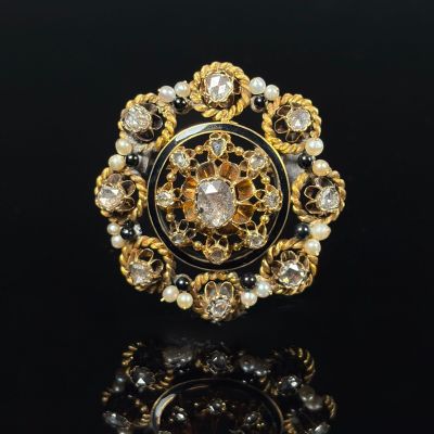 a close up of a ring with pearls and gold on a black surface