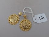 un gros plan sur une paire de boucles d'oreilles en or avec une étiquette