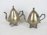 paire de théières anciennes en argent sur un support, sur fond blanc
