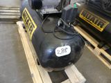 a black air compressor sitting on a pallet in a warehouse