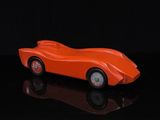 une petite voiture orange posée sur une surface noire