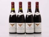 quatre bouteilles de vin sont alignées sur une surface blanche