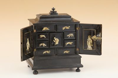 une commode noire et dorée dont la porte est ouverte