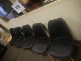 Plusieurs chaises noires sont alignées contre un mur dans un bureau.