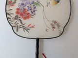 a fan with a bird on it hanging on a wall