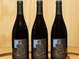 trois bouteilles de vin posées sur un tonneau