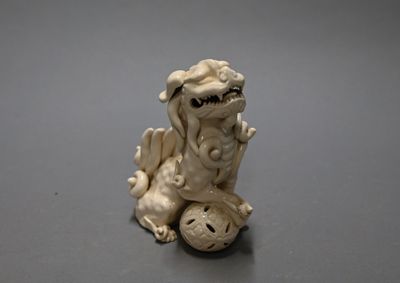 a small figurine of a dragon sitting on top of a ball