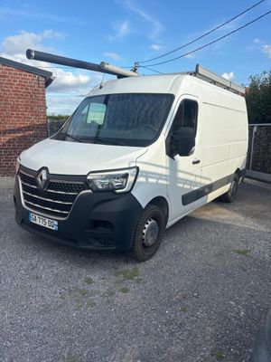 La camionnette blanche est garée sur le parking, à côté d'un bâtiment en briques.
