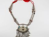 a silver necklace with a red tassel and beads