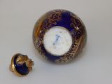 a small blue and gold vase with a clock on it