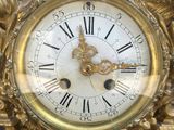 a gold clock with roman numerals on the face