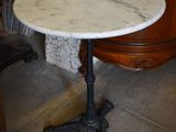 une table en marbre avec un piètement noir et un meuble en bois à l'arrière-plan