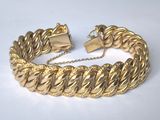 gros plan d'un bracelet en or sur une surface blanche
