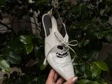 une personne tenant une paire de chaussures blanches devant un arbre