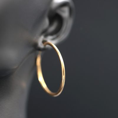 a close up of a gold hoop earrings on a mannequin head