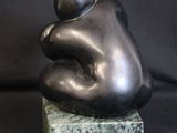 sculpture of a person sitting on a marble block on a black background