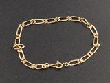 gros plan d'un bracelet en chaîne en or sur une surface noire