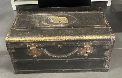 une vieille malle posée par terre à côté d'une table