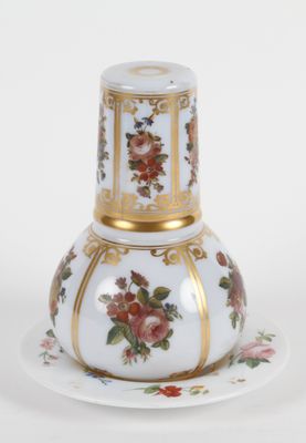 un vase blanc et doré posé sur une soucoupe, elle-même posée sur une assiette