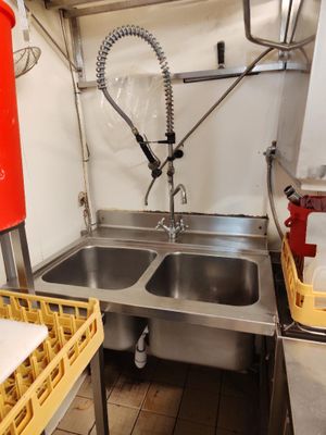 une cuisine avec un évier dans lequel se trouve un seau rouge