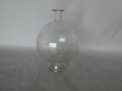 a clear glass vase sitting on a table with a white wall in the background