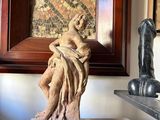 a statue of a woman holding a child on top of a book shelf